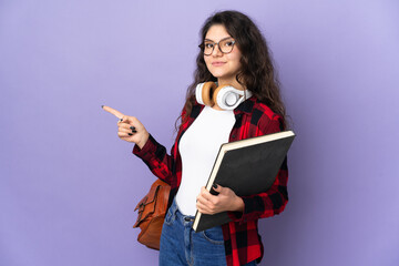 Teenager student isolated on purple background pointing finger to the side