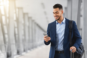 Handsome Young Arab Businessman Using Smartphone While Standing At Airport Terminal