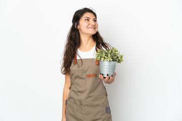 Young Russian gardener girl holding a plant isolated thinking an idea while looking up