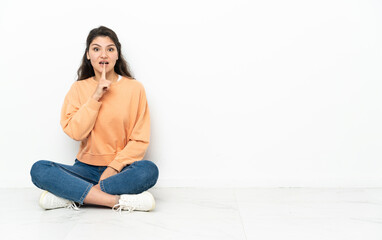 Teenager Russian girl sitting on the floor showing a sign of silence gesture putting finger in mouth