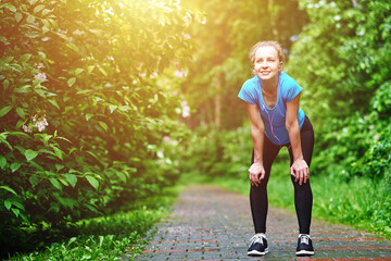 Tired woman runner having rest after running hard on road in forest, bending forward, resting...