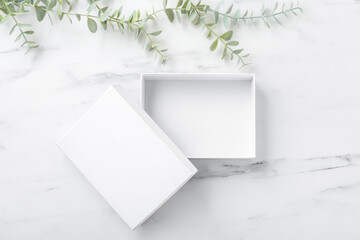 White box open on marble table with green plant