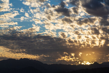 Dramatic scenes with cloudy sky and dark silhouette of Sinai mountains and orange sunset. Dahab, Sinai peninsula, Egypt