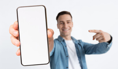 Stylish young man holding big smartphone with empty screen