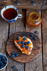 Obraz na płótnie Canvas Toast with butter, caramel and blueberries. Top view, wooden background.