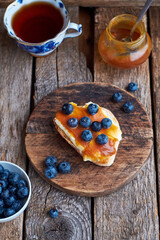 Toast with butter, caramel and blueberries. Top view, wooden background.
