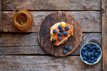 Toast with butter, caramel and blueberries. Top view, wooden background.