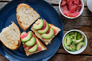 Toast with avocado and salmon. Top view, wooden background.