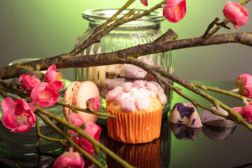 macaroon and cupcake on the table on a dark background near the jars for sweets