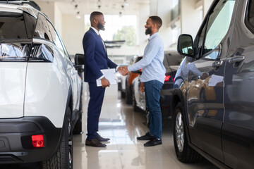 Auto Showroom Manager Shaking Hands With Male Customer After Successful Deal