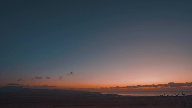 Dawn over the canary islands, time lapse. View of the island, ocean and electric wind turbines