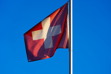 Swiss flag blowing in the wind at allotment on a sunny winter day. Photo taken January 26th, 2022, Zurich, Switzerland.