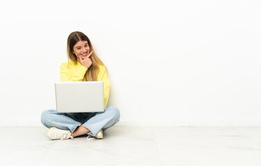 Young woman with a laptop sitting on the floor happy and smiling