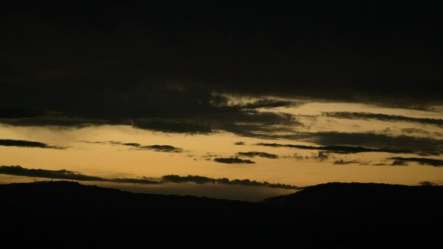 Beautiful Sunset and Silhouette of the hills with clouds rolling by.
