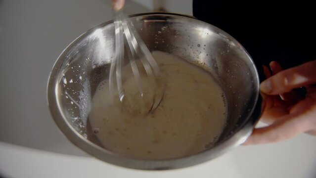 Young Female mixing yeast and milk for a cake in the kitchen at home. Homemade pastry close up