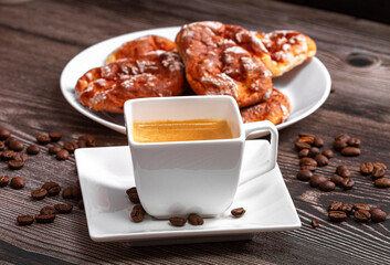A cup of signature espresso coffee in a scene of coffee beans and a wooden table top. Breakfast.