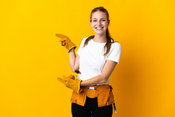 Young electrician woman isolated on yellow background surprised and pointing side