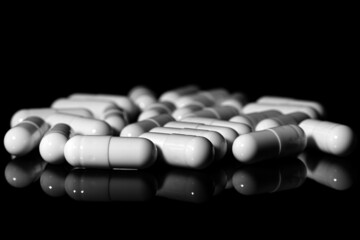 Close up of white painkiller capsule on a reflective black background