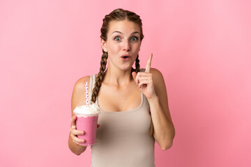 Young woman with strawberry milkshake isolated on pink background intending to realizes the solution while lifting a finger up
