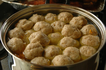 Large pot of chicken soup with matzah balls floating on the surface. 