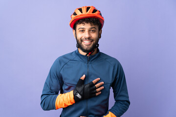 Young Moroccan cyclist man isolated on purple background smiling a lot - obrazy, fototapety, plakaty