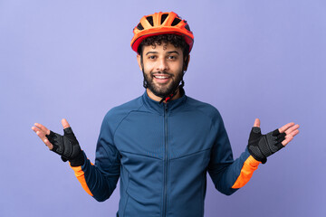 Young Moroccan cyclist man isolated on purple background with shocked facial expression - obrazy, fototapety, plakaty