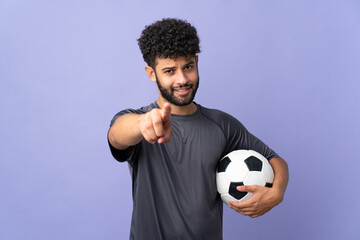 Handsome Moroccan young football player man over isolated on purple background pointing front with happy expression