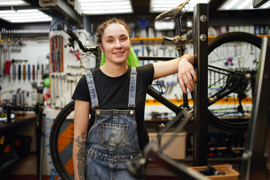 Cheerful woman working in bicycle workshop