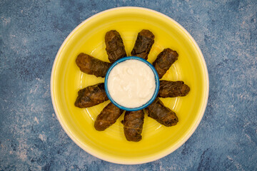 Meat leaf wrapping. Traditional Mediterranean flavor. Wrapped leaves with yogurt on a blue background. local name etli yaprak sarma