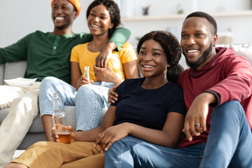 Closeup of happy black friends watching nice movie at home