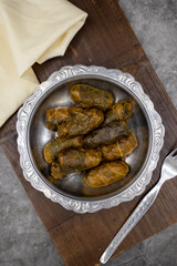 Meat leaf wrapping. Traditional Mediterranean flavor. Wrapped leaves with yogurt on a dark background. local name etli yaprak sarma