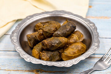 Meat leaf wrapping. Traditional Mediterranean flavor. Wrapped leaves with yogurt on a blue background. local name etli yaprak sarma