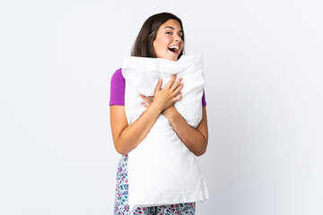 Fototapeta premium Young brazilian girl isolated on white background in pajamas and holding a pillow with happy expression
