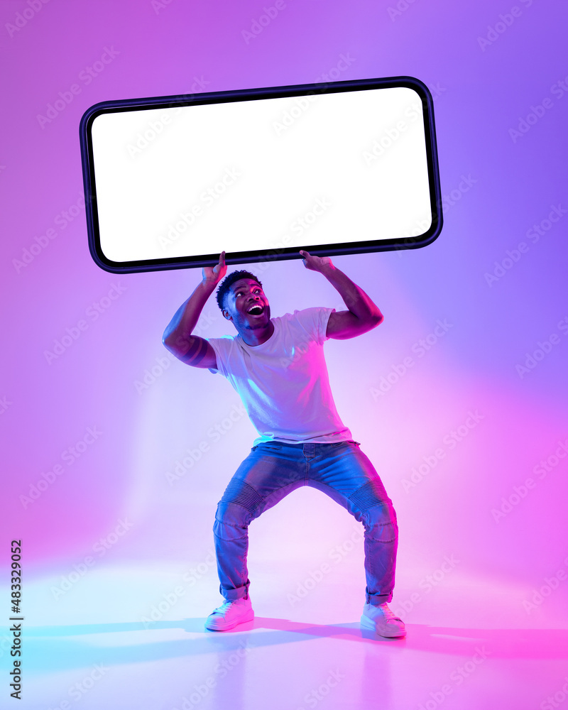 Poster black man holding big smartphone with empty screen in neon light. mockup for advertisement, mobile a