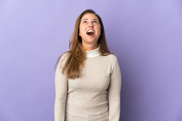 Fototapeta premium Middle age Brazilian woman isolated on purple background looking up and with surprised expression