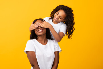 African American daughter covering her mother's eyes at studio