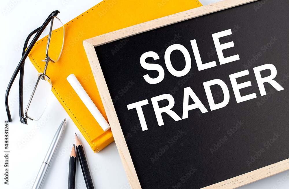 Poster sole trader text on the blackboard with notepad , pen, pencil