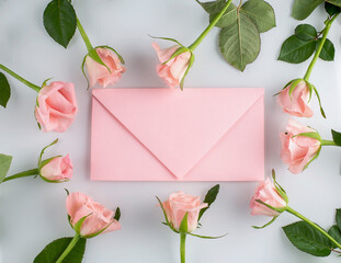 Pink roses and pink envelope on white background, copy space