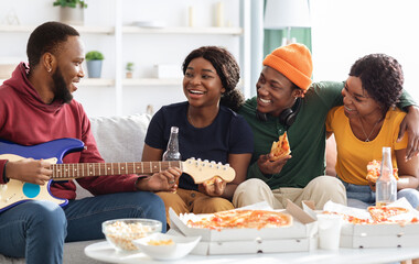 Cute black friends playing guitar and singing at home, panorama
