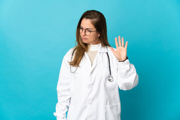 Middle age Brazilian doctor woman isolated on blue background making stop gesture and disappointed