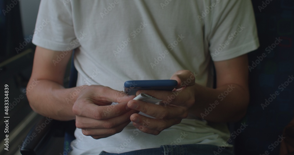 Poster student in white t-shirt using a mobile phone. anonymous, no face. he presses his fingers on the scr