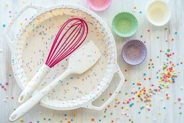 Silicone cake mould, spatula and whisk on wooden background.