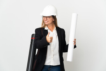 Middle age architect woman with helmet and holding blueprints over isolated background with thumbs...