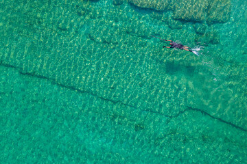 Spearfishing scuba diver in tropical exotic sea, ocean turquoise clear water. Man swimming hunting exotic fish, poaching. Top view. Aerial, drone, copter view.