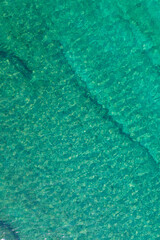 Background, texture of relaxing, calm turquoise, transparent sea water with stones, slabs, lump, coral. Summer vacation. Blue ocean lagoon. Drone, copter top view.