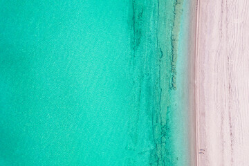 Relaxing aerial beach view with calm sea water and stone, slabs, lump, coral. Summer vacation. Blue ocean lagoon, sea shore, coastline. Drone, copter top view.