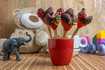 Chocolate covered strawberries on the background of kid's toys. Food ideas for kids. Homemade candies.