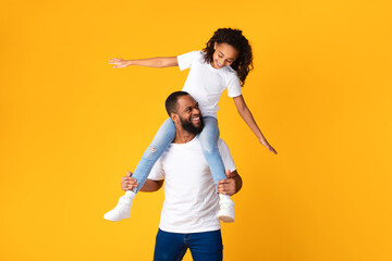 Cheerful African American Man Riding Excited Daughter On His Neck
