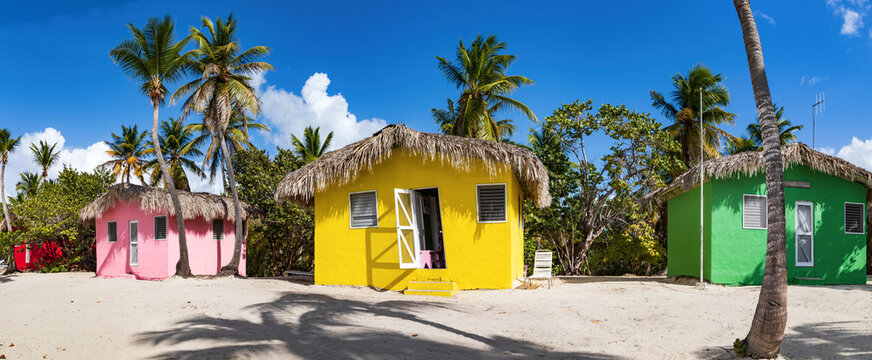 Isla Catalina, bunte H&auml;user zwischen Palmen am Strand der karibischen Insel in der Dominikanischen Republik, Panorama.