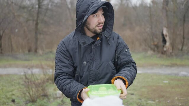 Man went on a picnic in early spring, close-up of the face of a man in a black jacket with a hood